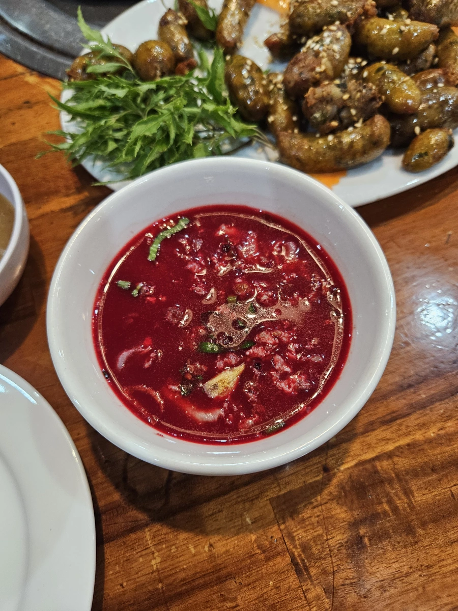 鮮血湯（疑似 Tiết canh 或動物血製品）、熟肉製品（背景盤中之香腸或肉塊）